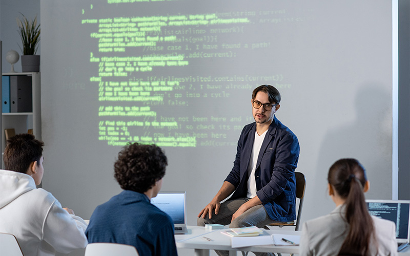 Instructor teaches programming to students with code projection.